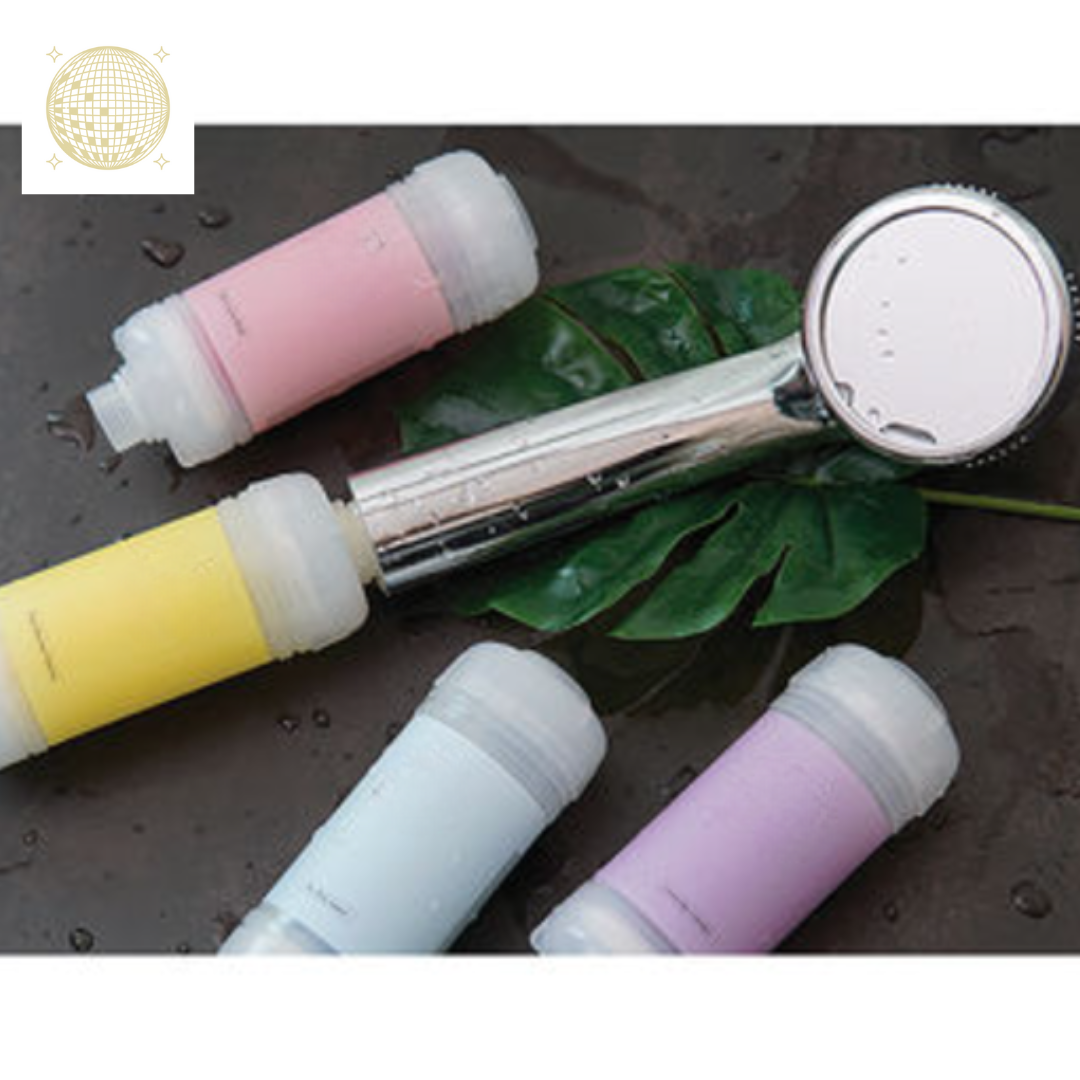 A chrome shower head and four vibrant shower filters in pink, yellow, light blue, and lavender lie on a wet dark surface with a green leaf
